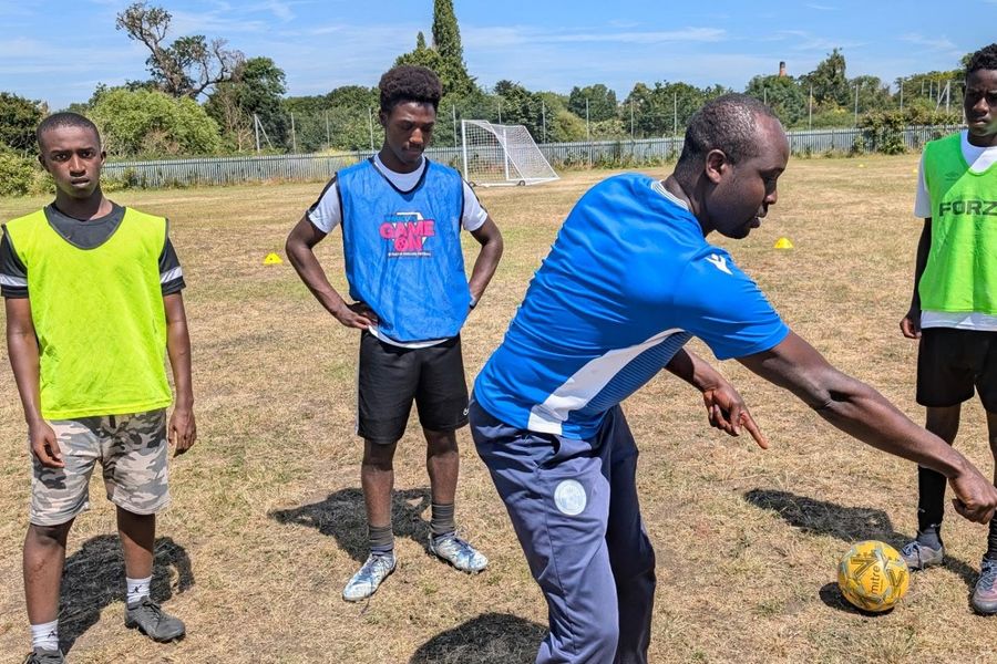 A coach demonstrating a drill to players in bibs