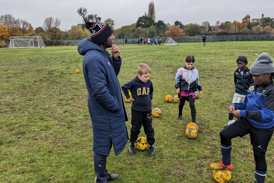 A coach with young Minikickers practising with footballs